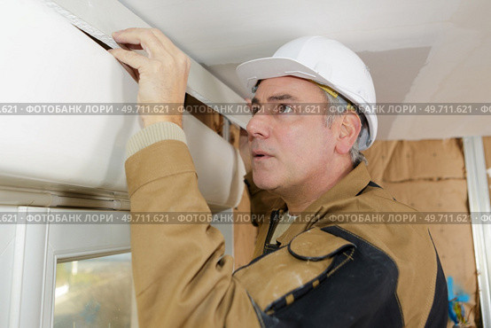 man worker adjusting blinds molding. Стоковое фото, агентство Ingram Publishing / Фотобанк Лори
