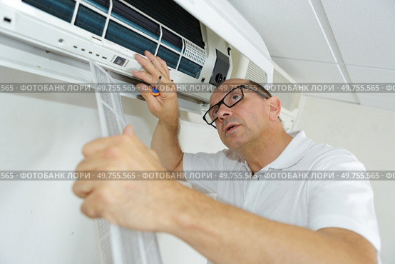 Man working on indoor air conditioning unit. Стоковое фото, агентство Ingram Publishing / Фотобанк Лори