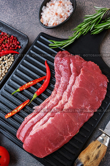 marbled beef bacon. black wooden cutting board with raw marbled beef bacon and seasonings, flat lay on taupe stone background. Стоковое фото, фотограф Оксана Медведева / Фотобанк Лори