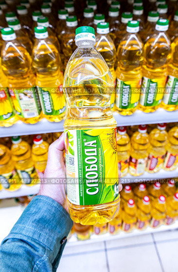 Масло подсолнечное «Слобода» в руке в супермаркете. Различные бутилированные подсолнечные масла. Редакционное фото, фотограф FotograFF / Фотобанк Лори