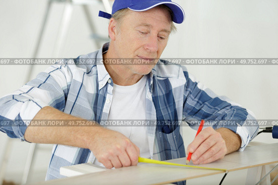 mature builder taking measures indoors. Стоковое фото, агентство Ingram Publishing / Фотобанк Лори