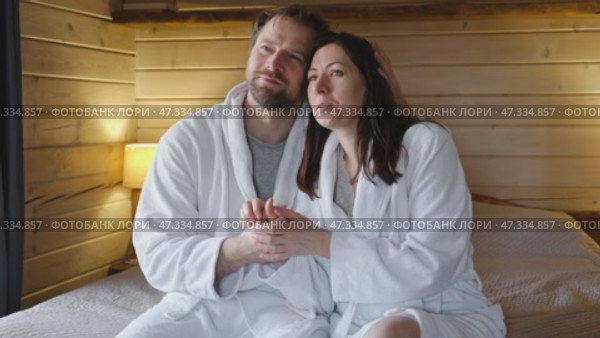 Mature couple in a white bathrobes hugging each other kissing at home bedroom. Intimate Moment. Tender embrace shared between a loving middle age man and woman, husband and wife. Deep love. Vacation. Стоковое видео, видеограф Марина Демидюк / Фотобанк Лори