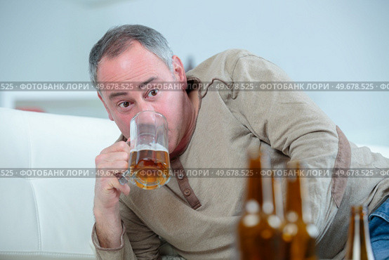 mature drunk man drinks a beer on the sofa. Стоковое фото, агентство Ingram Publishing / Фотобанк Лори