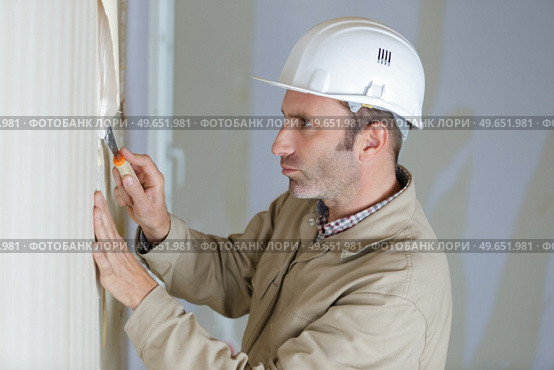 mature male builder stripping wallpaper with scraper. Стоковое фото, агентство Ingram Publishing / Фотобанк Лори