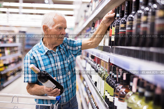Mature senor choosing alcoholic drinks in supermarket. Стоковое фото, фотограф Татьяна Яцевич / Фотобанк Лори
