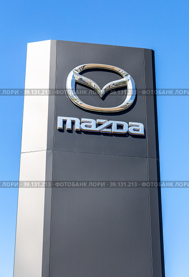 Mazda dealership sign against a blue sky background (2022 год). Редакционное фото, фотограф FotograFF / Фотобанк Лори