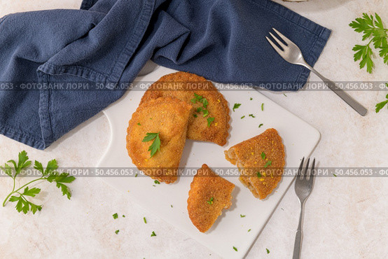 Meat patties and parsley leaves on white ceramic dishes in a kitchen counter top. Стоковое фото, агентство Ingram Publishing / Фотобанк Лори
