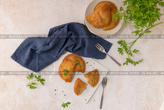 Meat patties and parsley leaves on white ceramic dishes in a kitchen counter top. Стоковое фото, агентство Ingram Publishing / Фотобанк Лори