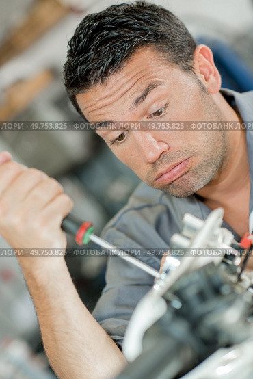 Mechanic using screwdriver, looking exhausted. Стоковое фото, агентство Ingram Publishing / Фотобанк Лори