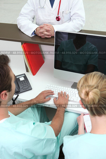 Medical assistant looking at his reflection on a computer screen. Стоковое фото, агентство Ingram Publishing / Фотобанк Лори
