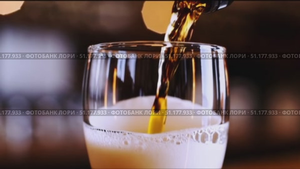 Medium close-up of a straight-sided pint filled with light-amber lager; dense white foam against a cool blue/black background. 4K MP4, no people. Стоковое AI-видео, аниматор Владислав Войтов / Фотобанк Лори