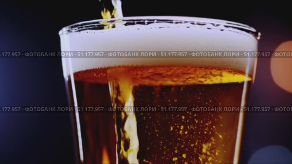 Medium close-up of a straight-sided pint filled with light-amber lager; dense white foam against a cool blue/black background. 4K MP4, no people. Стоковое AI-видео, аниматор Владислав Войтов / Фотобанк Лори