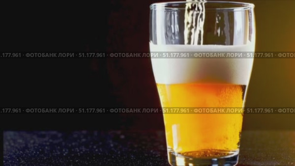 Medium close-up of a straight-sided pint filled with light-amber lager; dense white foam against a cool blue/black background. 4K MP4, no people. Стоковое AI-видео, аниматор Владислав Войтов / Фотобанк Лори