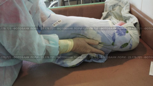 Медсестра в перчатках пеленает новорожденного на пеленальном столике в роддоме. Стоковое видео, видеограф Александр Багно / Фотобанк Лори