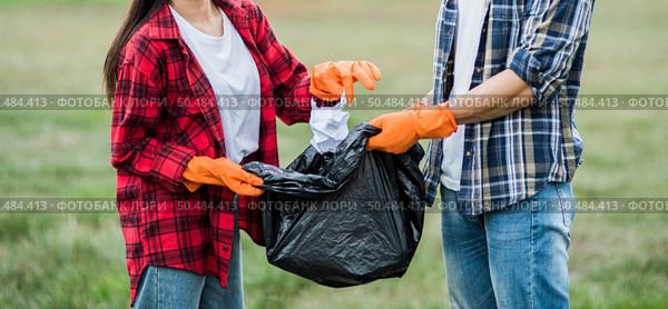 Men and women helped to collect garbage in a black bag. Стоковое фото, агентство Ingram Publishing / Фотобанк Лори