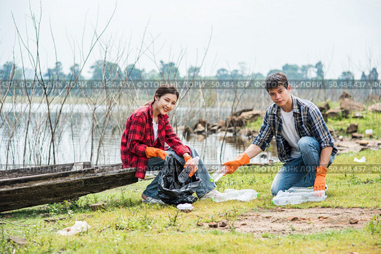 Men and women helped to collect garbage in a black bag. Стоковое фото, агентство Ingram Publishing / Фотобанк Лори