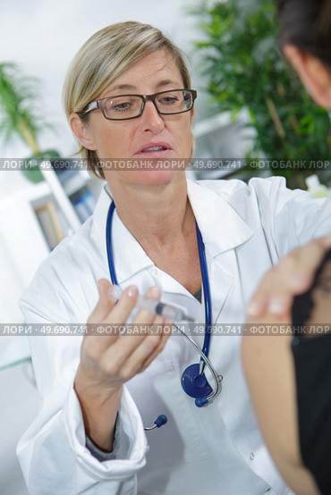 middle-age female doctor injecting vaccine isolated on white. Стоковое фото, агентство Ingram Publishing / Фотобанк Лори