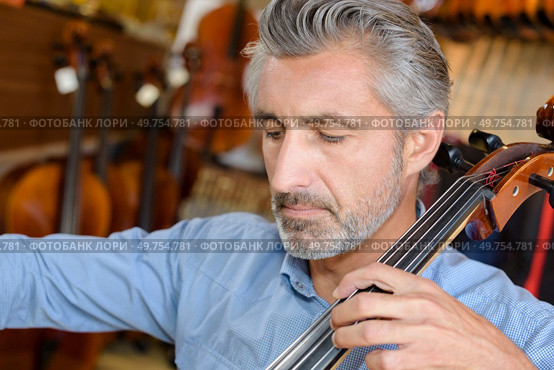 Middle aged man playing stringed instrument. Стоковое фото, агентство Ingram Publishing / Фотобанк Лори