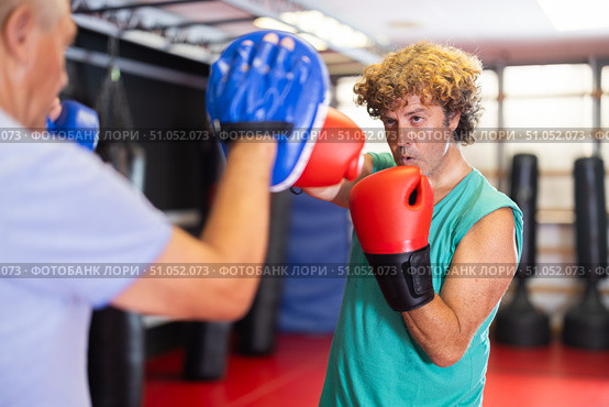 Middle‑aged man practicing punches on mitts with partner. Стоковое фото, фотограф Яков Филимонов / Фотобанк Лори