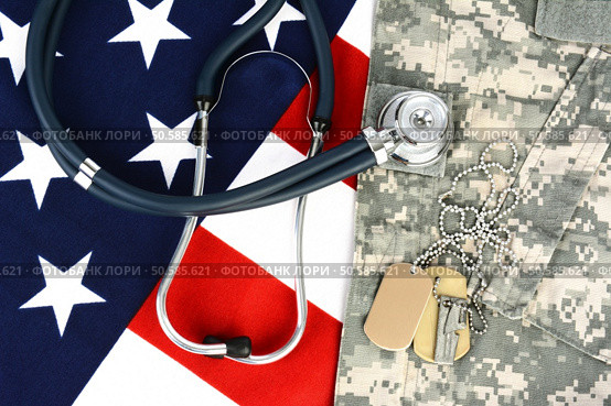 Military fatigues and dog tags on an American Flag with a stethoscope to illustrate health care in the armed services. Horizontal format, fills the frame. Стоковое фото, агентство Ingram Publishing / Фотобанк Лори
