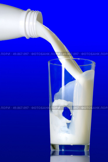 Milk pouring in glass on blue background. Стоковое фото, агентство Ingram Publishing / Фотобанк Лори