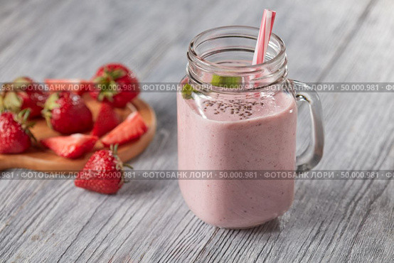 Milk smoothie with strawberries, mint leaves and chia seeds in a glass jar with a straw on a wooden table with copy space. Healthy drink. Healthy milk drink with strawberries, chia seeds and fresh mint leaves in a jar with a straw on a gray wooden background with copy space. Стоковое фото, агентство Ingram Publishing / Фотобанк Лори
