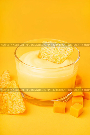 Миска с вкусным сырным соусом чеддер и накос на желтом фоне. Стоковое фото, фотограф Pixel_shot / Фотобанк Лори