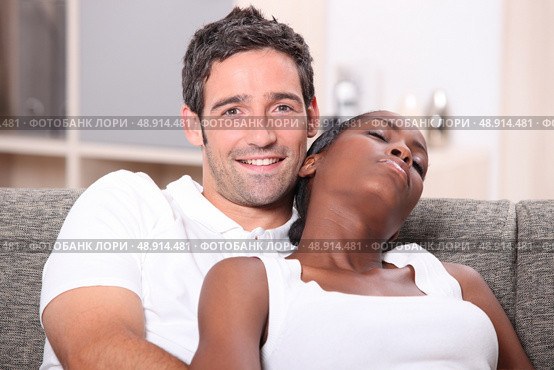 Mixed race couple relaxing on the sofa. Стоковое фото, агентство Ingram Publishing / Фотобанк Лори