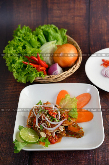 Mixed sardine salad was beautiful arrangement in white plate, stainless spoon and fork on napkin, blurred sardine with tomato sauce and cooking ingredient in weave basket placed nearly on wooden table. Стоковое фото, агентство Ingram Publishing / Фотобанк Лори