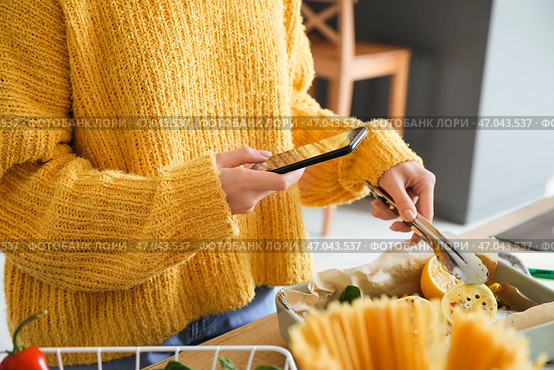 Молодая женщина фотографирует форму для запекания с рыбой и овощами на кухне. Стоковое фото, фотограф Pixel_shot / Фотобанк Лори