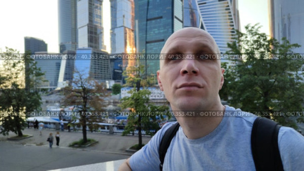 Молодой человек восхищается архитектурой современного города. Мужчина наблюдает за тем, что происходит вокруг. Стеклянные здания и набережная реки на заднем плане. Смотровая площадка возле небоскребов. A young man admires the architecture of a modern city. The man is watching what is happening around. Glass buildings and the river embankment in the background. Observation deck near skyscrapers. Стоковое видео, видеограф Ирина / Фотобанк Лори