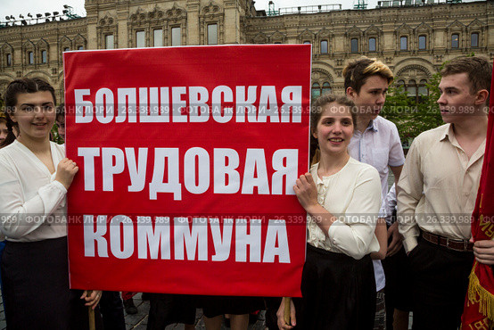 Молодые люди держат плакат с надписью "Болшевская трудовая коммуна" на Красной площади города Москвы во время церемонии приема в пионеры, Россия (2017 год). Редакционное фото, фотограф Николай Винокуров / Фотобанк Лори