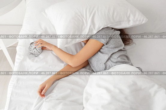 Morning of young woman sleeping with alarm clock in bed. Стоковое фото, фотограф Pixel_shot / Фотобанк Лори