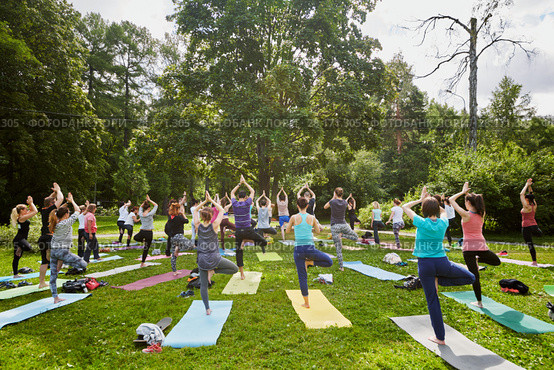 MOSCOW, RUSSIA - JUL 09, 2016: Men and women make exercises during yoga training on grass at summer day in park. Yoga is a group of practices which originated in ancient India. Редакционное фото, фотограф Losevsky Pavel / Фотобанк Лори