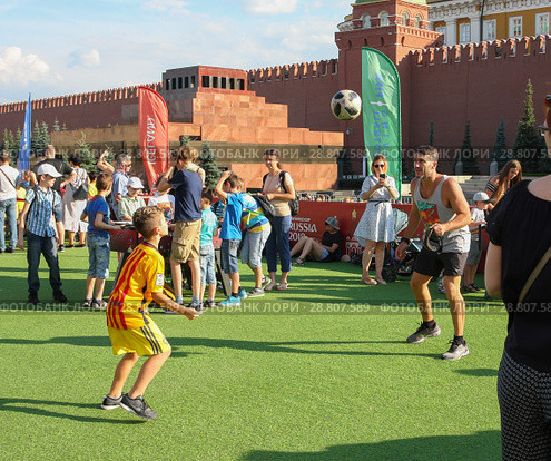 Москва, Красная площадь. В Парке футбола мужчина и мальчик в спортивной форме играют в футбол на фоне Кремлевской стены. FIFA, чемпионат мира 2018. Редакционное фото, фотограф Наталья Николаева / Фотобанк Лори