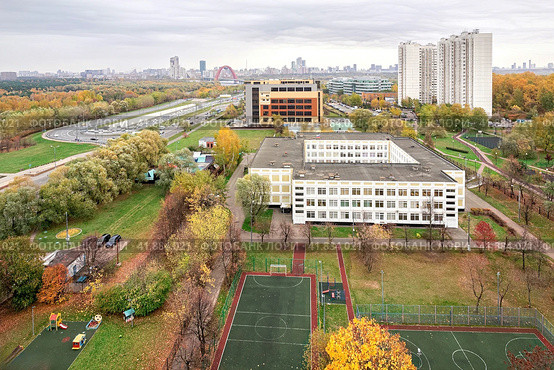 Москва, Россия, октябрь 2023 года. Вид на район Крылатское с высоты. Зеленый сквер, спортивная площадка, школа, жилые дома, гаражный комплекс, дорога, вид на Москву сквозь осеннюю дымку. (2022 год). Редакционное фото, фотограф Сергей Никифоров-Гордеев / Фотобанк Лори