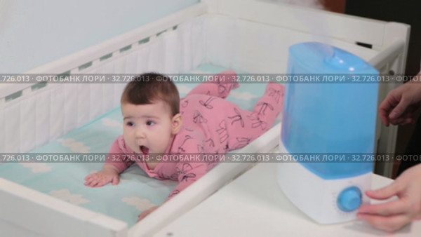 Mother brings her baby in crib and turns on the humidifier for infant comfort sleeping. Стоковое видео, видеограф Кекяляйнен Андрей / Фотобанк Лори