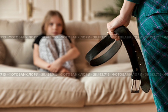 Mother wants to punish her child daughter with belt in hand. Angry mom punishes teen girl for offense and hits baby with belt. Concept of family quarrels, problems and parenting. Copy text space. Стоковое фото, фотограф Aleksandr Golubev / Фотобанк Лори