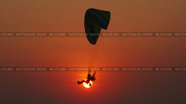 Motor paraglider flying through colorful sunset sky. Стоковое фото, фотограф Михаил Коханчиков / Фотобанк Лори