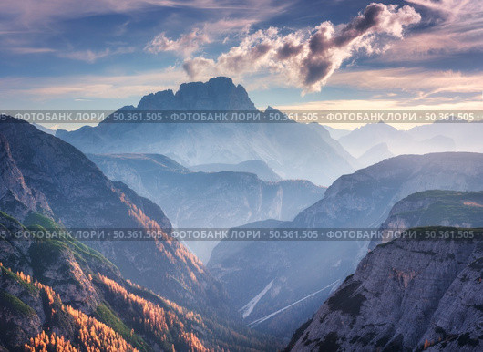 Mountain canyon lighted by bright sunbeams at sunset in autumn in Dolomites, Italy. Landscape with mountain ridges, rocks, colorful trees and orange grass, alpine meadows, gold sunlight in fall. Alps. Стоковое фото, агентство Ingram Publishing / Фотобанк Лори