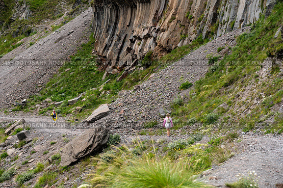 Mountain trekking. Hiker with trekking sticks climbs steep on mountain trail. Mountain landscape. Tourism, sport life style concept. Стоковое фото, фотограф Павел Муравьев / Фотобанк Лори