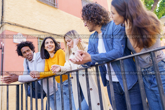 Multi-ethnic group of friends gathered in the street leaning on a railing. Young people having fun together.. Multi-ethnic group of friends gathered in the street leaning on a railing. Стоковое фото, агентство Ingram Publishing / Фотобанк Лори