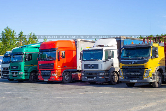 Multicolored trucks stand in a row in a parking lot, long distance cargo transportation (2020 год). Редакционное фото, фотограф Коханова Наталья / Фотобанк Лори