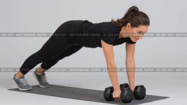 Muscular female athlete performing renegade rows with weights, balancing on fitness mat against white backdrop, demonstrating core strength during exercise training. Стоковое AI-видео, аниматор Юрий Поздников / Фотобанк Лори