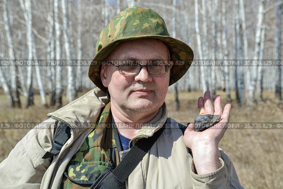 Мужчина держит в руке фрагмент Челябинского метеорита, найденного  весной 2013 года недалеко от города Чебаркуль. Стоковое фото, фотограф Александр Бушков / Фотобанк Лори