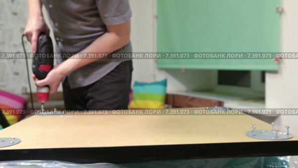 Мужчина собирает мебель с помощью электрической дрели. Стоковое видео, видеограф Кекяляйнен Андрей / Фотобанк Лори