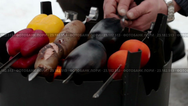 Мужчина ставит шашлык с овощами и сосисками на дровяной печи. Стоковое видео, видеограф ActionStore / Фотобанк Лори