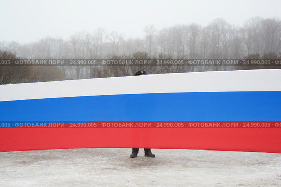 Мужчина стоит за транспарантом с российским триколором на митинге (2017 год). Стоковое фото, фотограф Иван Козлович / Фотобанк Лори