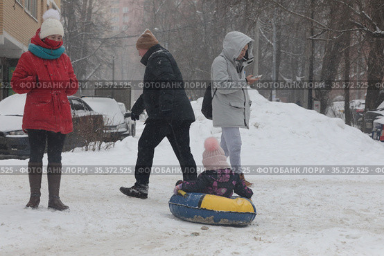 Мужчина везёт ребёнка на балоне по снегу (2021 год). Редакционное фото, фотограф Дмитрий Неумоин / Фотобанк Лори