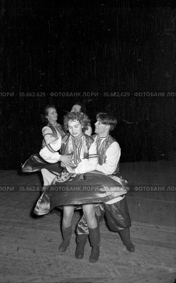 Мужчины и женщины исполняют русские народные танцы на сцене, молодые люди и девушки одеты в национальную одежду и пляшут парами, самодеятельность сотрудников педагогического училища, Якутия, декабрь 1959. Редакционное фото, фотограф Варфоломей Тетерин / Фотобанк Лори